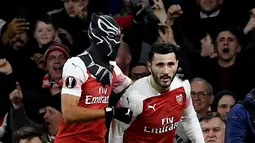 Striker Arsenal Pierre-Emerick Aubameyang (kiri) mengenakan topeng superhero Black Panther usai mencetak gol ke gawang Stade Rennes pada leg kedua babak 16 besar Liga Europa di Stadion Emirates, London, Inggris  (14/3). (Reuters/Tony O'Brien)