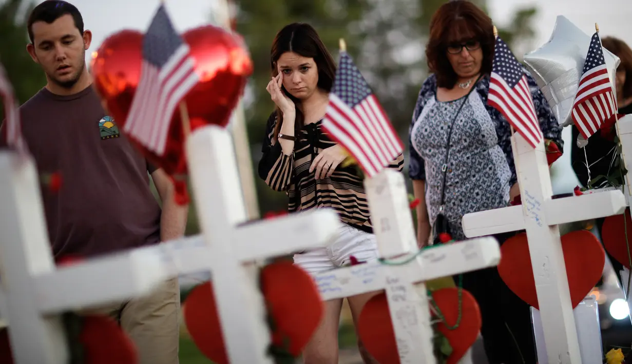 Sejumlah orang mengamati nisan untuk menghormati korban tewas penembakan massal yang terjadi dekat Kasino Mandalay Bay di Las Vegas, Jumat (6/10). Sebanyak 58 nisan kayu berbentuk salib itu ditambahkan ornamen hati berwarna merah. (AP/Gregory Bull)