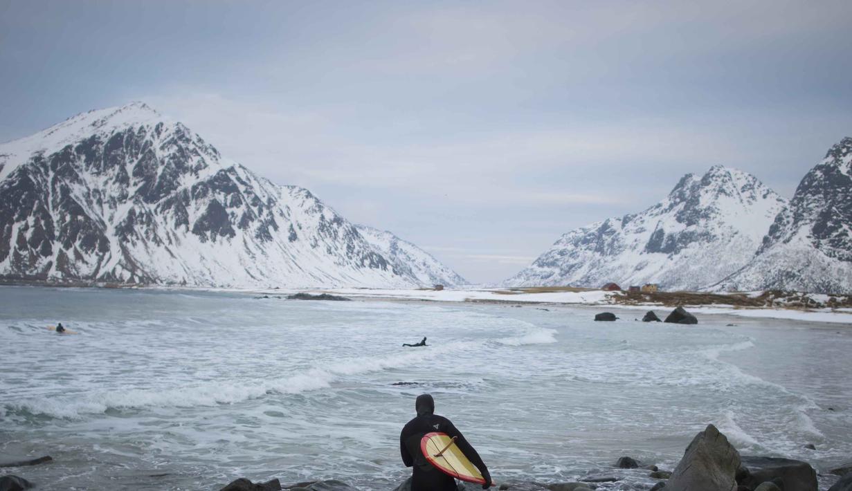 Seorang peselancar tengah bersiap untuk beraksi  di kawasan pantai  Flackstad, dekat Ramberg, kepulauan Lofoten, Arctic Circle, (10/3/2016). (AFP/Olivier Morin)