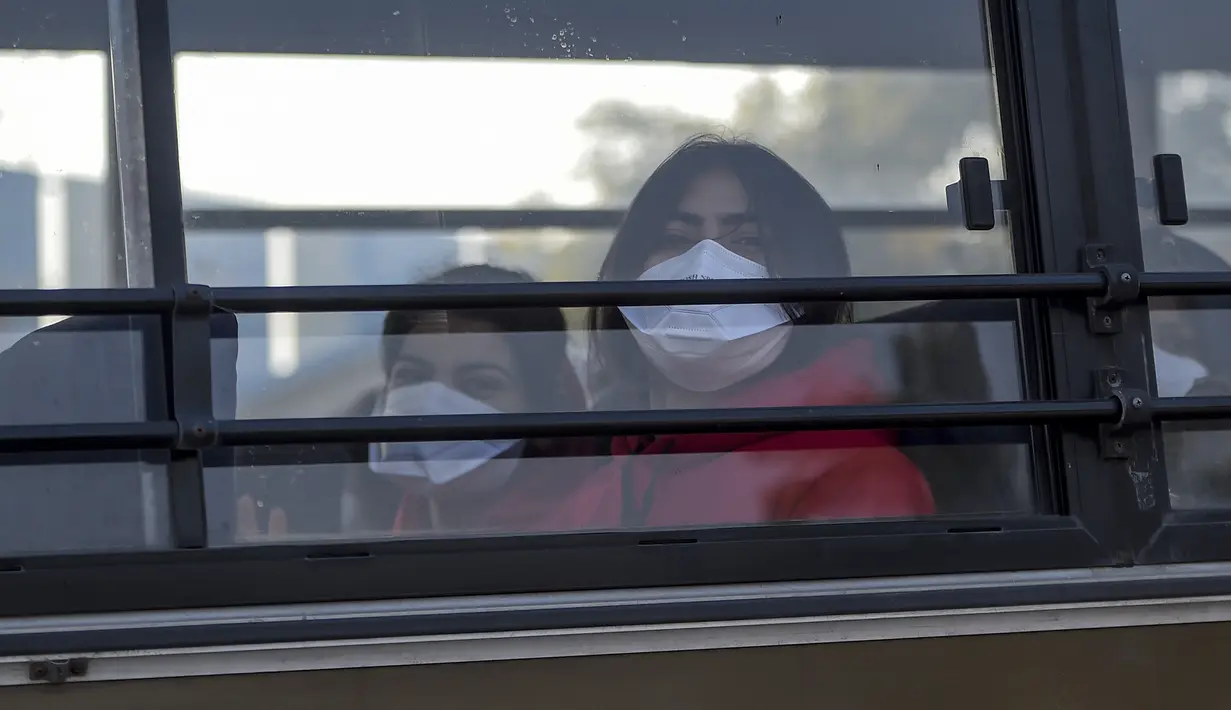Dua wanita India mengenakan masker berada di dalam bus saat keluar dari Bandara Internasional Indira Gandhi setelah dievakuasi dari kota Wuhan di China, di New Delhi (1/2/2020). Jumlah total kematian akibat wabah virus corona di China tercatat mencapai 259 hingga Jumat (31/1/2020). (AFP/Money Sharma