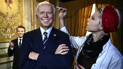 Penata rias memberikan sentuhan akhir pada patung lilin Presiden AS Joe Biden yang baru diresmikan di museum lilin Musee Grevin di Paris, Selasa (18/5/2021). Museum tersebut diperkirakan akan dibuka kembali pada 19 Mei 2021 setelah ditutup berbulan-bulan karena COVID-19. (Christophe ARCHAMBAULT/AFP)