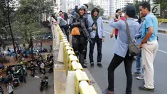 Mahasiswa dari salah satu perguruan tinggi berfoto dengan personel Brimob usai melakukan aksi unjuk rasa di sekitar Jembatan Layang Gerbang Pemuda, Jakarta, Selasa (1/10/2019). Mahasiswa dari berbagai perguruan tinggi kembali berunjuk rasa menolak beberapa RUU. (Liputan6.com/Helmi Fithriansyah)