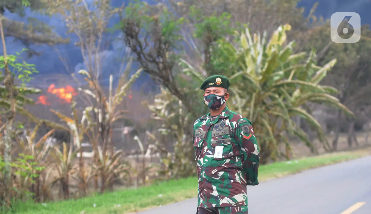 Anggota TNI berjaga di lokasi terbakarnya kilang minyak di Jalan Raya Balongan-Indramayu, Kabupaten Indramayu, Jawa Barat, Senin (29/3/2021).  Dampak dari terbakarnya kilang minyak Balongan milik PT Pertamina itu mengakibatkan Jalan Raya Balongan-Indramayu ditutup total. (merdeka.com/Arie Basuki)