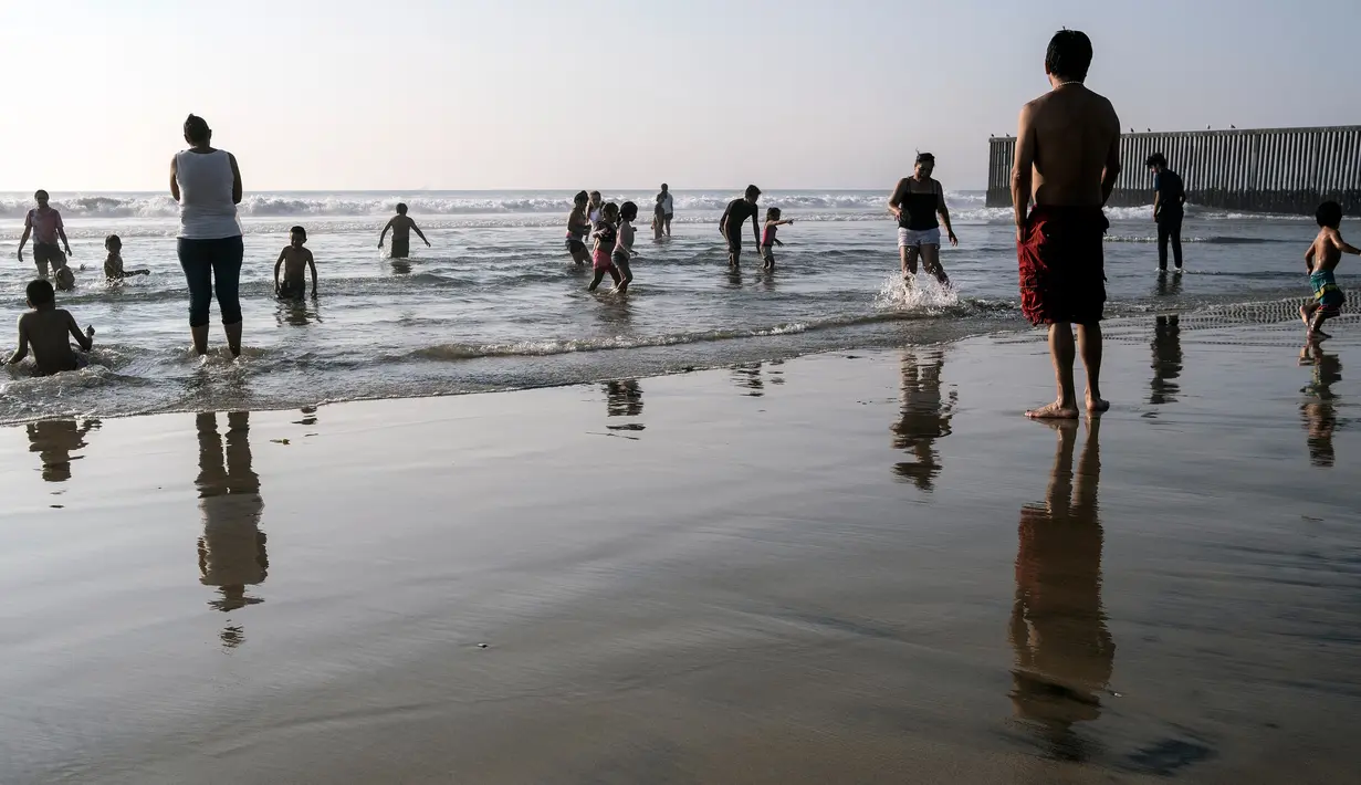 Orang-orang mengunjungi pantai di Playas de Tijuana dekat perbatasan AS-Meksiko di Tijuana Meksiko, Sabtu (3/10/2020). Akhir pekan ini pantai di Playas de Tijuana dibuka kembali dengan pembatasan pengunjung, setelah ditutup sejak Maret lalu guna mencegah penyebaran Covid-19. (Guillermo Arias/AFP)