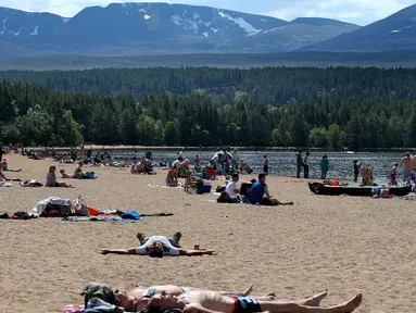 Orang-orang berjemur di pantai di Loch Morlich dekat Aviemore, di Skotlandia, (28/5). Cuaca panas tengah melanda sebagian besar wilayah di Inggris. (AP Photo/Jane Barlow)