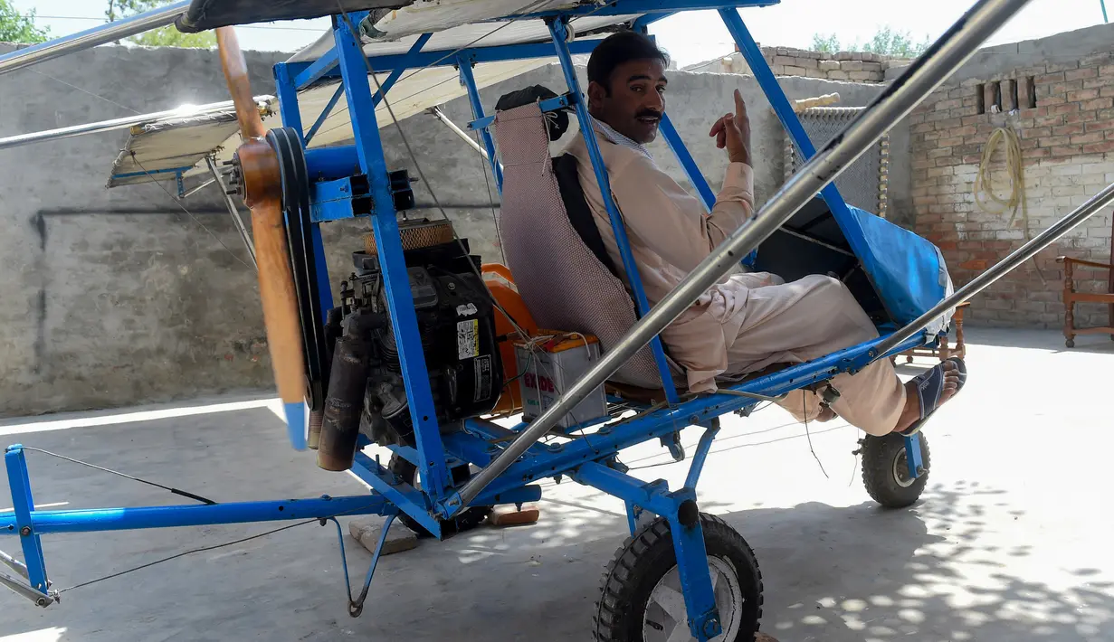 Muhammad Fayyaz duduk dalam pesawat buatannya di Desa Tabur, Provinsi Punjab, Pakistan, 8 April 2019. Penjual popcorn asal sebuah desa di Pakistan tersebut sukses membuat pesawat sendiri dari alat seadanya. (ARIF ALI/AFP)