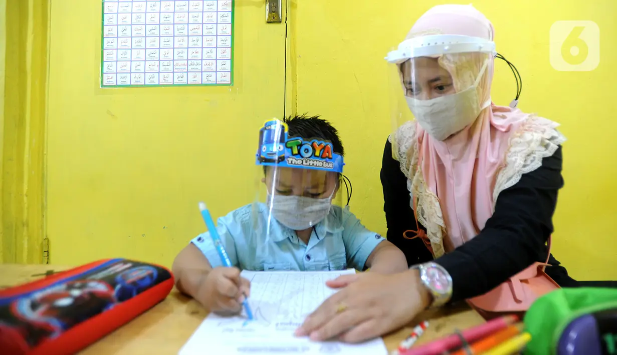 Guru menggunakan face shield saat mengajari murid di Taman Pendidikan Al-Qur'an (TPA) Al-Muthmainnah Cinere, Depok, Rabu (1/7/2020). Jadwal murid diatur dalam beberapa sesion waktu (pagi siang sore) sebagai wajud penerapan sosial distancing dalam kelas. (merdeka.com/Arie Basuki)