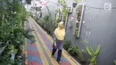 Warga melintas di salah satu gang kampung hijau di kawasan Malakasari, Jakarta, Sabtu (15/9). Tingginya kesadaran masyarakat akan pentingnya tumbuhan membuat kawasan tersebut terlihat asri dan dipenuhi berbagai tanaman. (Liputan6.com/Immanuel Antonius)