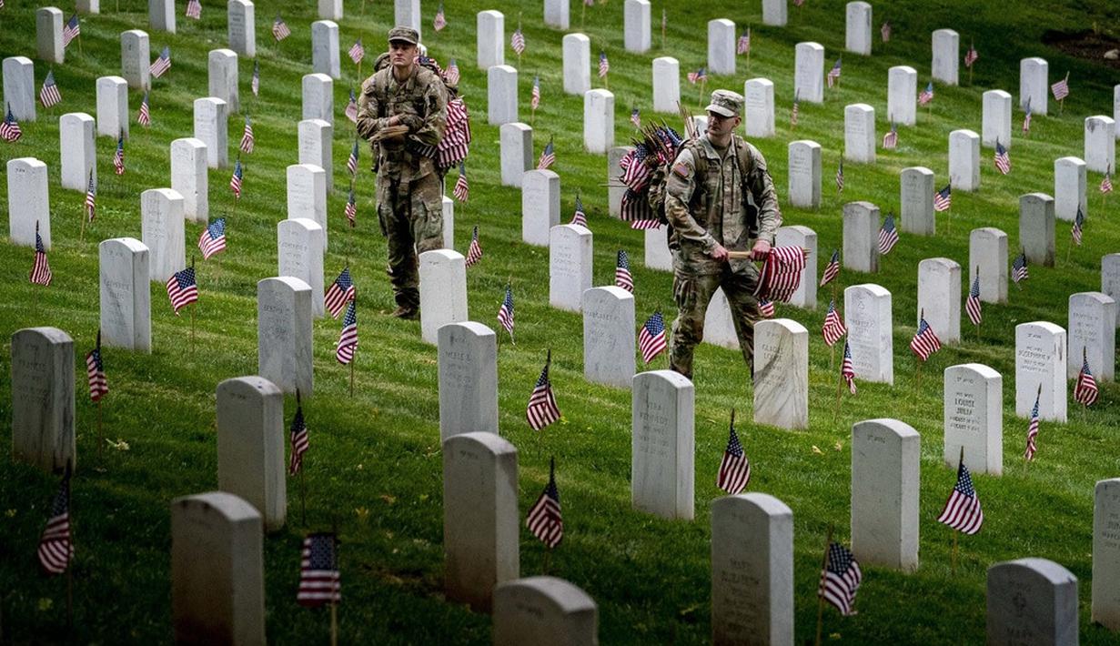 <p>Anggota Resimen Infantri ke-3 Amerika Serikat yang juga dikenal sebagai The Old Guard menempatkan bendera pada setiap nisan untuk aksi "Flags-In" jelang Memorial Day di Pemakaman Nasional Arlington, Arlington, Amerika Serikat, Kamis (25/5/2023). Kegiatan ini untuk menghormati pahlawan militer Bangsa yang gugur. (AP Photo/Andrew Harnik)</p>