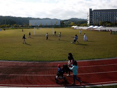 Pengungsi Afghanistan bermain sepak bola di taman bermain Institut Pengembangan Sumber Daya Manusia Nasional di Jincheon, Korea Selatan (13/10/2021). Para pengungsi muncul di hadapan publik pada hari Rabu, untuk pertama kalinya sejak mereka tiba pada akhir Agustus. (AFP/Pool/Jeon Heon-kyun)