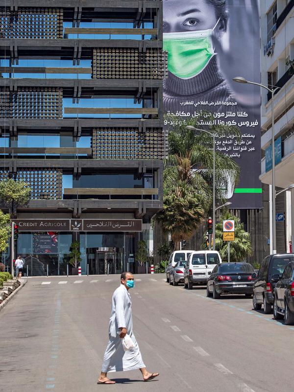 Sebuah gambar yang diambil pada 24 Mei 2020 menunjukkan seorang pria berjalan melintasi jalan yang sepi di Rabat, saat negara itu menerapkan lockdown untuk menghentikan penyebaran Covid-19 , pada hari pertama Idul Fitri. (Photo by FADEL SENNA / AFP)