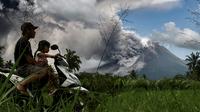 Pengendara motor melintas saat erupsi Gunung Merapi terlihat dari desa Tunggularum di Sleman pada 11 Maret 2023. Berdasarkan pengamatan pada Sabtu (11/3/2023) mulai pukul 06.00-12.00 WIB, BPPTKG mencatat satu kali guguran lava keluar dari Gunung Merapi dengan jarak luncur maksimal 1.500 meter ke arah barat daya. (AFP/Devi Rahman)