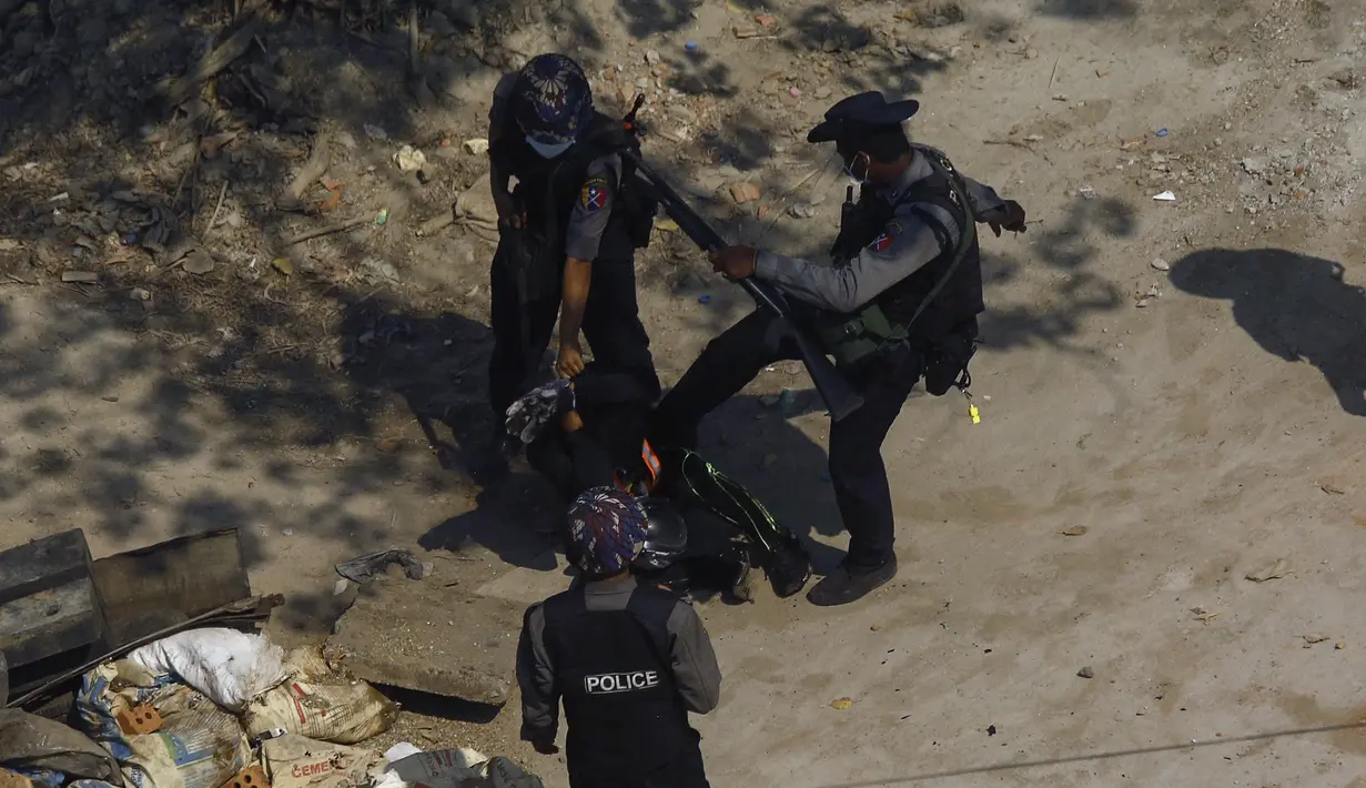 Polisi menendang seorang pengunjuk rasa saat mereka menahannya selama demonstrasi menentang kudeta militer di Yangon, Sabtu (6/3/2021). Sedikitnya 55 orang telah tewas sejak kudeta militer 1 Februari. (AFP Photo)