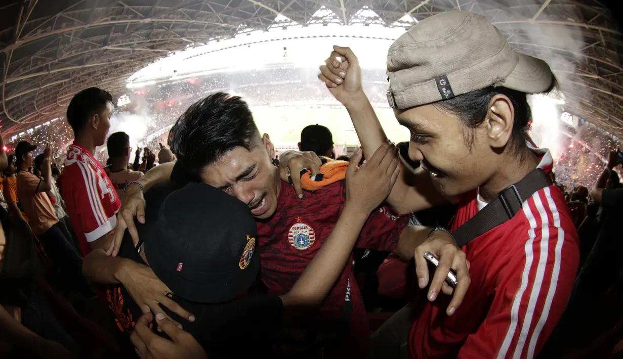 Suporter Persija Jakarta berpelukan saat merayakan gelar juara Liga 1 di SUGBK, Jakarta, Minggu (09/12). Persija menang 2-1 atas Mitra Kukar. (Bola.com/M Iqbal Ichsan)