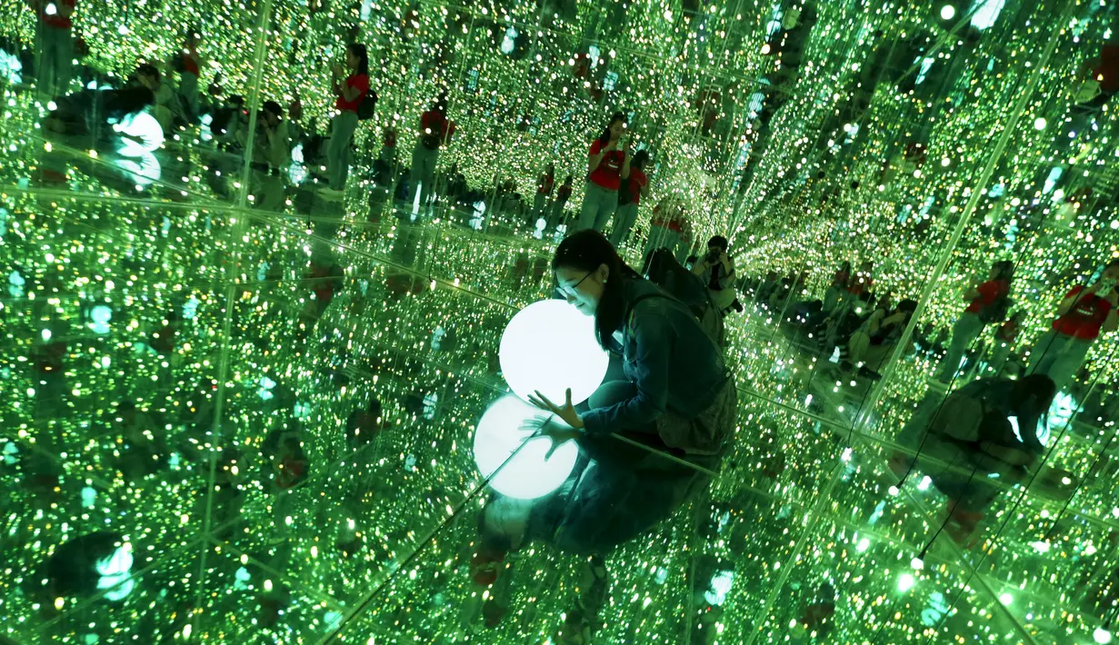 Seorang pengunjung memegang lampu saat berpose di instalasi ilusi optik dalam pameran Imagine Your Museum of Art di Beijing, Tiongkok, Jumat (2/10/2015). (REUTERS/Jason Lee)