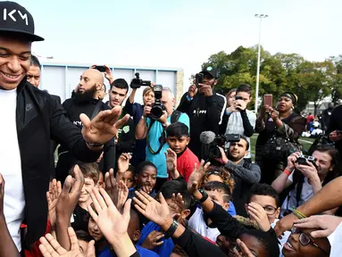 Bintang Prancis, Kylian Mbappe, menyapa anak-anak saat mengunjungi markas AS Bondy di Paris, Rabu (17/10). Kunjungan ke klub pertamanya ini dilakukan setelah dirinya meraih gelar Piala Dunia 2018. (AFP/Franck Fife)