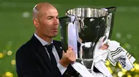 Pelatih Real Madrid, Zinedine Zidane, mengangkat trofi juara La Liga musim 2019/2020 usai timnya mengalahkan Villarreal pada laga lanjutan La liga di Estadio Alfredo Di Stefano, Jumat (17/7/2020) dini hari WIB. (AFP/Gabriel Bouys)