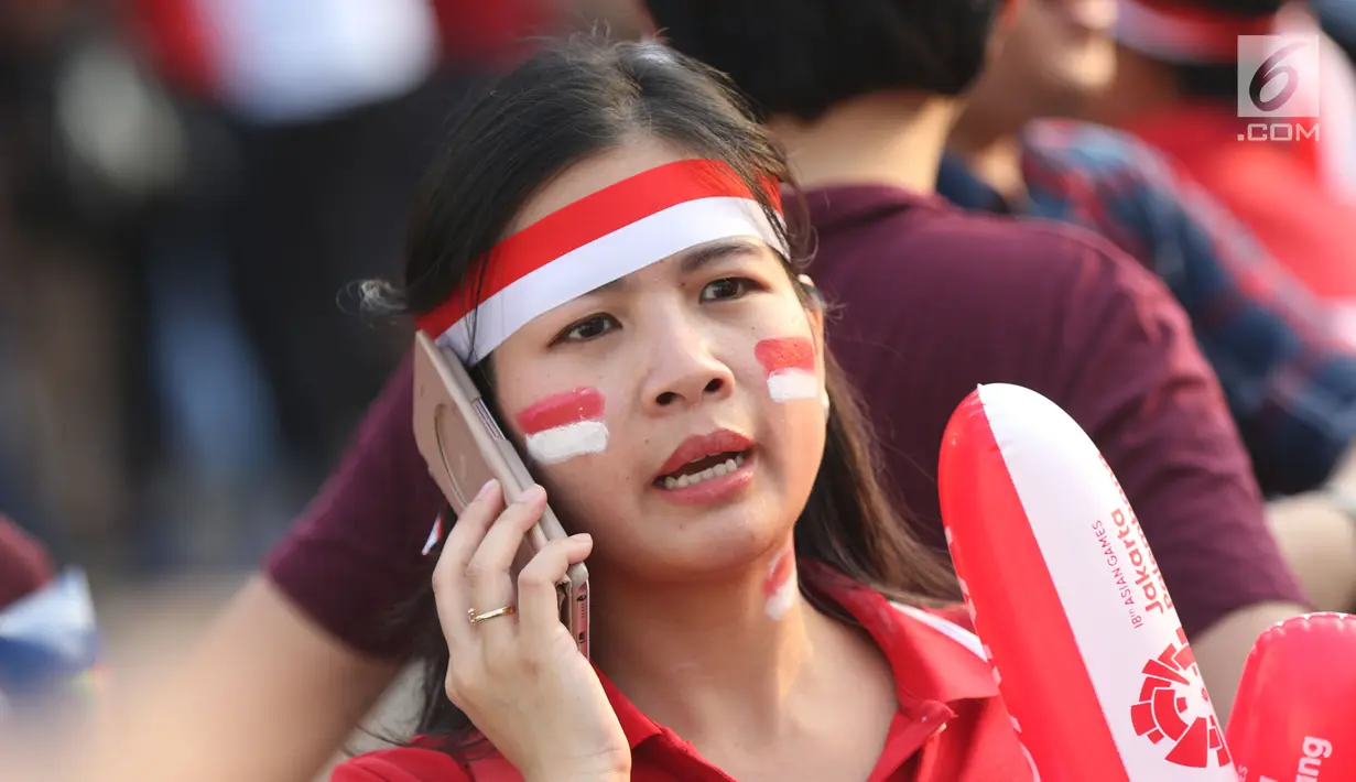 Calon penonton menggunakan hiasan saat antre masuk menyaksikan laga final bulu tangkis beregu putra di Istora Senayan Jakarta, Rabu (22/8). Laga final bulu tangkis beregu putra mempertemukan Indonesia melawan China. (Liputan6.com/Helmi Fithriansyah)