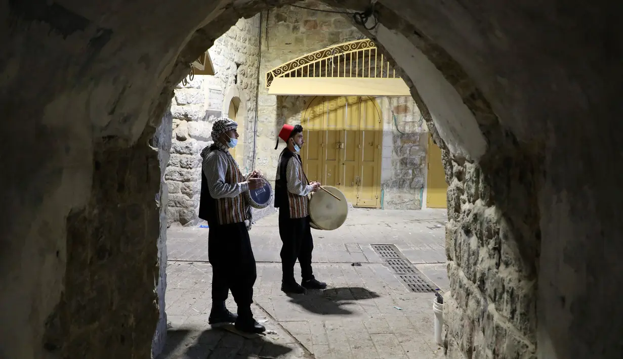 Pria Palestina yang dikenal dengan "Musaharatis" saat bertugas sebagai "penabuh drum Ramadhan" di kota tua Hebron, Tepi Barat pada 14 April 2021. Membangunkan sahur sudah menjadi tradisi yang sudah mereka lakukan selama Ramadhan. (HAZEM BADER/AFP)