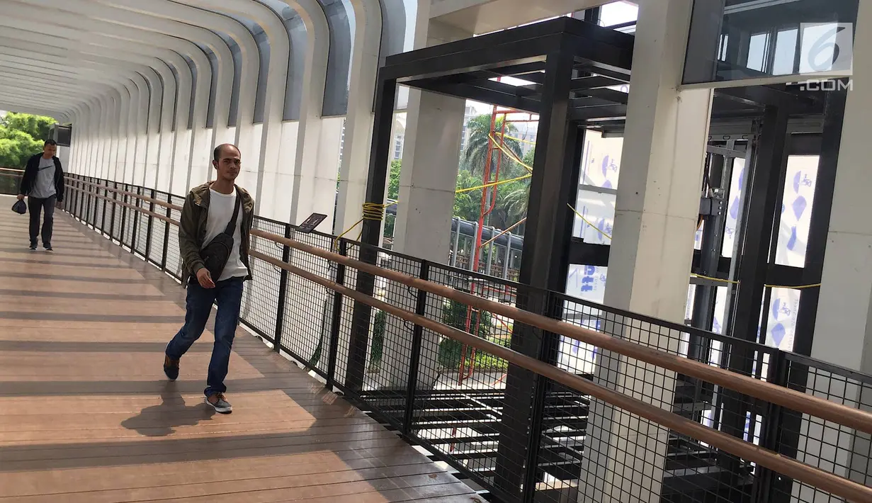 Pejalan kaki melintas di dekat pembangunan lift pada jembatan penyeberangan orang di Jakarta, Senin (13/5). Pembangunan lift pada tiga JPO yang berada di Jalan Sudirman itu bertujuan meningkatkan kenyamanan kepada warga dan ditargetkan rampung akhir bulan ini.(Liputan6.com/Immanuel Antonius)