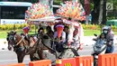 Delman hias membawa penumpang melintasi di sekitar Silang Merdeka Barat Daya, Jakarta, Selasa (19/6). Masa libur Lebaran 2018 dimanfaatkan warga untuk berwisata di sekitar Monumen Nasional dengan menaiki delman hias. (Liputan6.com/Helmi Fithriansyah)