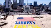 Foto udara yang diambil pada Jumat 4 Juli 2025 menunjukkan instalasi pasir yang menggambarkan bendera Amerika Serikat (AS) dan slogan “Liberty for All” atau Kebebasan untuk Semua di salah satu pantai di luar kantor cabang Kedutaan Besar (Kedubes) Amerika Serikat (AS) di Tel Aviv, Israel. (Jack GUEZ/AFP)