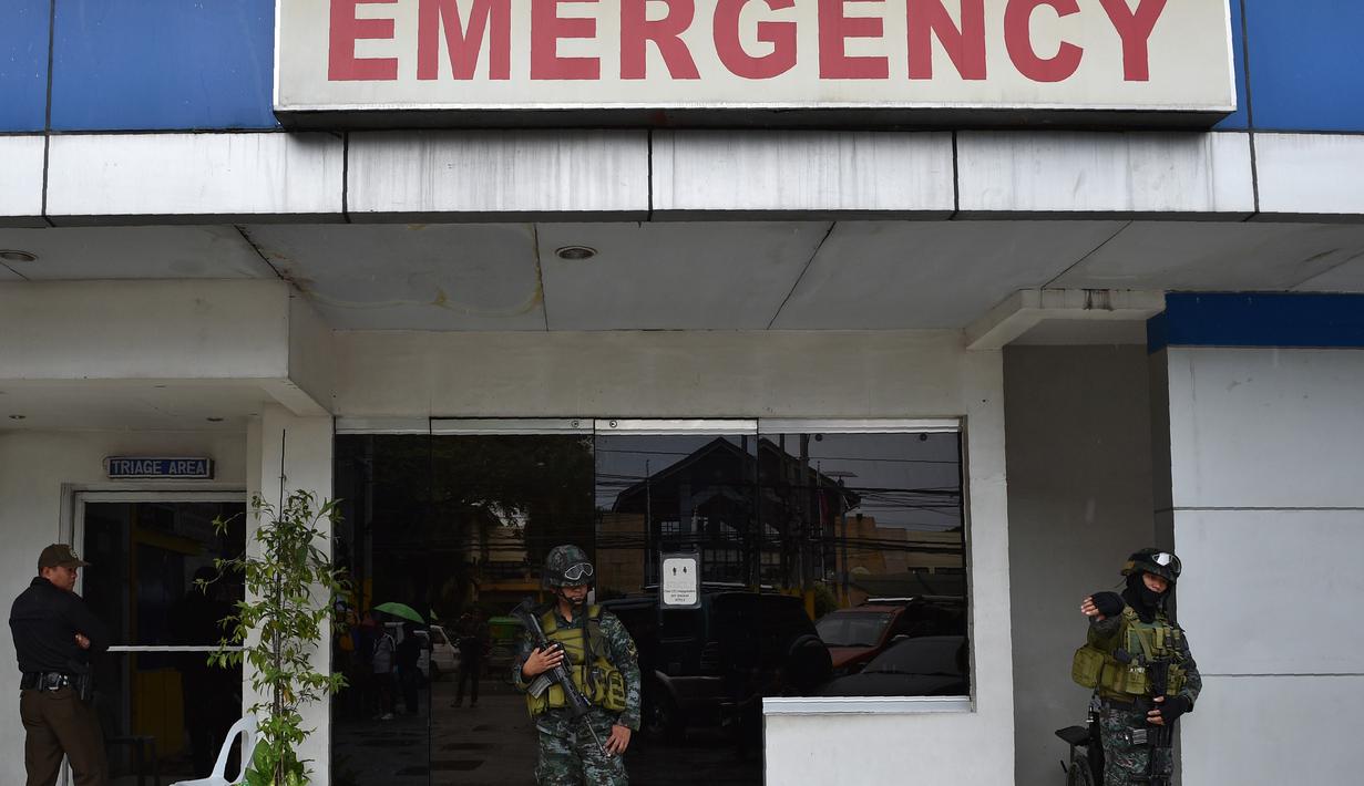 Sejumlah polisi pasukan khusus berjaga di pintu masuk gawat darurat menyusul kerusuhan yang terjadi di sebuah penjara di Filipina, Rabu (28/9). Selain menewaskan satu anggota geng narkoba, kerusuhan itu juga melukai tiga napi lainnya. (TED Aljibe/AFP)