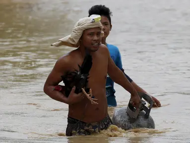 Seorang warga tampak membawa tabung gas dan hewan peliharaanya melewati jalanan yang banjir pasca bencana badai topan Koppu di Nueva Ecija,  Filipina, Senin (19/10/2015). Badai terjadi pada Minggu pagi waktu setempat. (REUTERS/Erik De Castro)