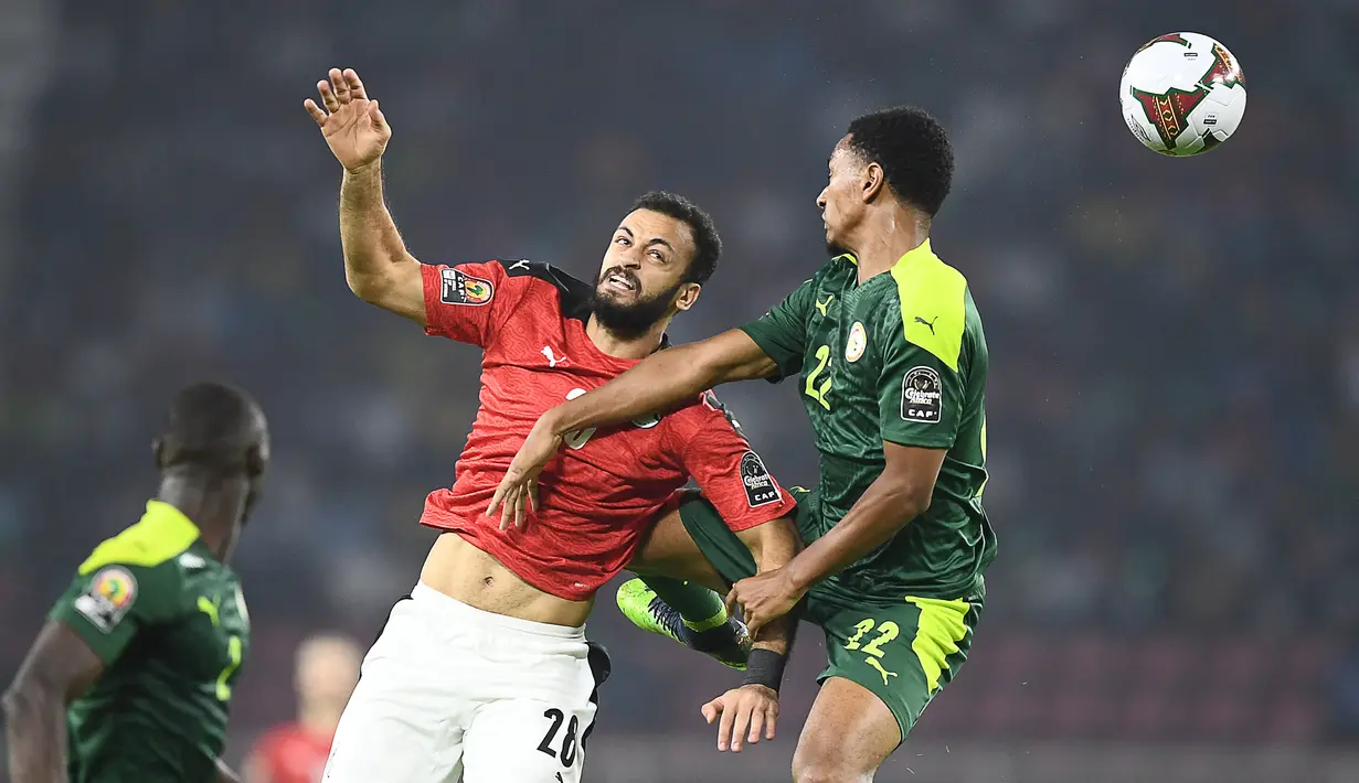 Pemain depan Mesir Marwan Hamdi (kiri) menyundul bola dengan bek Senegal Abdou Diallo pada pertandingan final Piala Afrika 2021 di Paul Biya Stadium, Kamerun, Senin (7/2/2022) dini hari WIB. Sadio Mane membawa Senegal mengalahkan Mesir lewat adu penalti dengan skor 4-2. (CHARLY TRIBALLEAU / AFP)