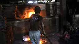 Seorang pria menyalakan oven kayu untuk membuat roti di toko roti Bongu di lingkungan Bel Air di Port-au-Prince, Haiti, Senin (27/9/2021).  (AP Photo/Rodrigo Abd)