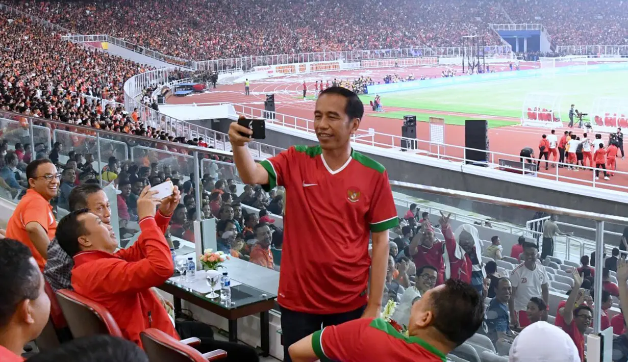 Presiden Joko Widodo (Jokowi) tampak asyik membuat vlog dengan kamera handphone saat menyaksikan laga final Piala Presiden 2018 antara Persija Jakarta vs Bali United di Stadion Utama Gelora Bung Karno, Sabtu (17/2). (Liputan6.com/Pool/Biro Pers Setpres)