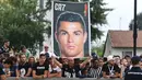 Suporter Juventus membawa spanduk saat menyambut kedatangan pemain baru Juventus Cristiano Ronaldo untuk menjalani tes medis di pusat layanan kesehatan Juventus (J-Medical) di Turin, Italia, (16/7). (AFP Photo/Miguel Medina)