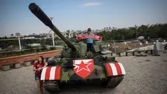Suporter Red Star Belgrade berpose di tank T-55 yang terparkir di tribun utara Stadion Rajko Mitic, Belgrade, Serbia, Selasa (27/8/2019). Kehadiran tank tersebut memicu protes dari pihak Kroasia yang sempat berperang merebut kemerdekaannya dari Yugoslavia. (OLIVER BUNIC/AFP)