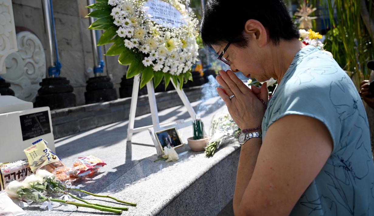 Seorang wanita asal Jepang berdoa di Monumen Bom Bali, Kuta, dekat Denpasar pada Sabtu (12/10/2019). MeMperingati 18 tahun peristiwa bom Bali yang terjadi pada 12 Oktober 2002, wisatawan dan kerabat korban mengunjungi tugu peringatan untuk berdoa dan tabur bunga. (SONNY TUMBELAKA / AFP)