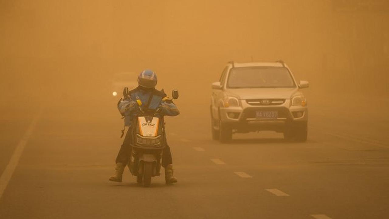 Seorang pengendara motor tampak berhati-hati ketika berkendara di tengah badai pasir yang menerjang Kota Jilin, Provinsi Jilin, China, pada 28 Maret 2024. Terpaan badai pasir parah yang melanda China ini disebabkan oleh cuaca dingin dan angin kencang.&nbs