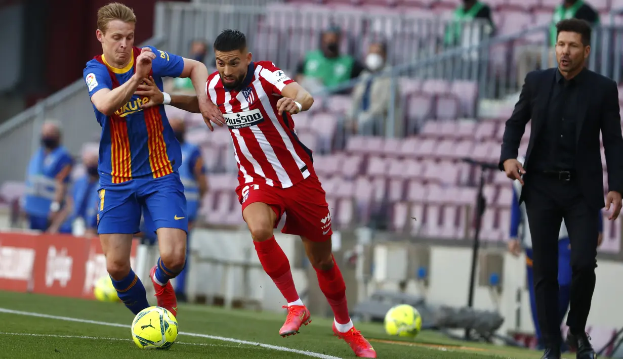 Pelatih Atletico Madrid, Diego Simeone (kanan)  menyaksikan pemainnya Yannick Carrasco memperebutkan bola dengan gelandang Barcelona, Frenkie de Jong selama pertandingan lanjutan La Liga Spanyol di stadion Camp Nou di Barcelona, Spanyol, Sabtu (8/5/2021). (AP Photo / Joan Monfort)