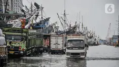 Aktivitas pekerja bongkar muatan kapal saat banjir rob di Pelabuhan Sunda Kelapa, Jakarta, Senin (6/12/2021). Banjir rob kembali merendam kawasan Pelabuhan Sunda Kelapa sejak pagi tadi hingga ketinggian 70 cm dan menyebabkan terganggunya aktivitas bongkar muatan kapal. (merdeka.com/Iqbal S Nugroho)