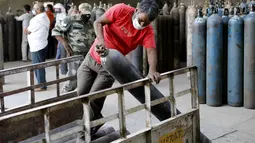 Pekerja memuat tabung oksigen di stasiun pengisian di pinggiran Prayagraj, India, pada 23 April 2021. Otoritas India bergegas membawa tangki oksigen ke rumah sakit tempat pasien COVID-19 tercekik di tengah gelombang virus corona terburuk di dunia. (AP Photo/Rajesh Kumar Singh)