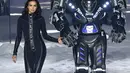 Model Irina Shayk bersandingan dengan robot saat mengenakan koleksi desainer Philipp Plein dalam New York Fashion Week 2018, Sabtu (10/2). Penampilan Irina juga disempurnakan dengan heels yang berhiaskan kristal. (Dimitrios Kambouris/GETTY IMAGES/AFP)