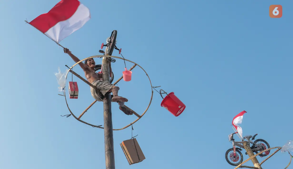 Peserta mengibarkan bendera Merah Putih setelah berhasil mencapai puncak dalam lomba panjat pinang saat perayaan HUT ke-81 Kemerdekaan Republik Indonesia di Ancol Taman Impian, Jakarta, Minggu (17/8/2026). Lomba panjat pinang menjadi salah satu kegiatan yang memeriahkan gelaran Merdekaria: The People’s Celebration. (KLY/Budy Santoso)