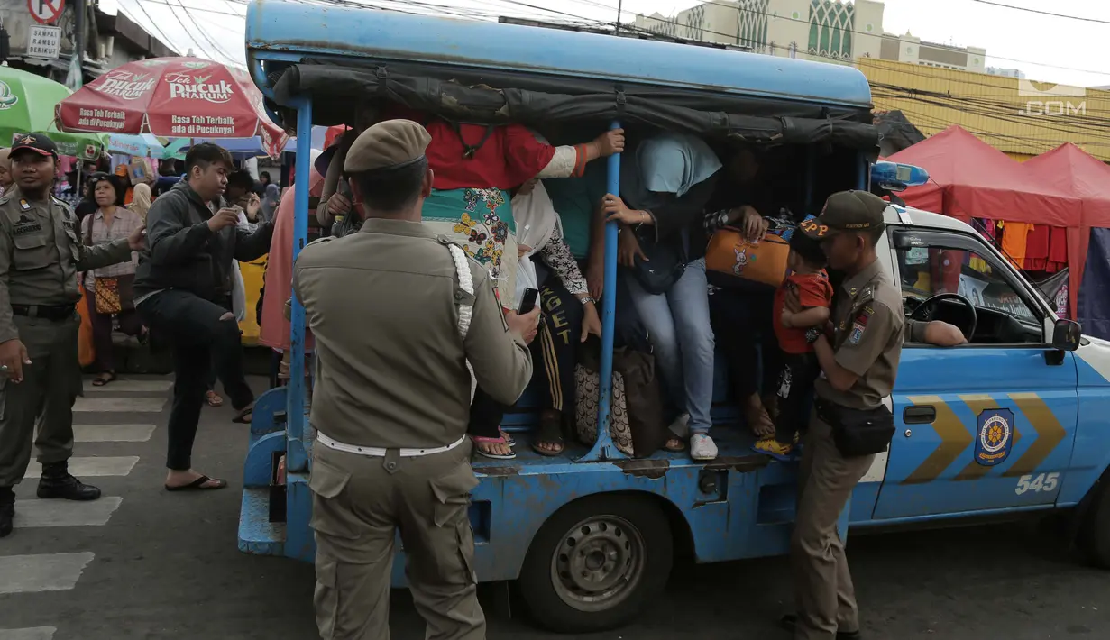 Petugas Satpol PP membantu warga menaiki mobil patroli mereka di jalan Jatibaru Raya, Jakarta, Selasa (30/1). Operasional bus Tanah Abang Explorer dihentikan sementara imbas dari mogok supir angkutan umum di Tanah Abang. (Liputan6.com/Gempur M Surya)