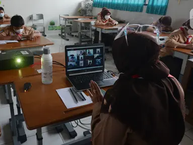 Guru mengajar para murid saat uji coba pembelajaran tatap muka di SDN Malaka Jaya 07 Jakarta, Rabu (9/6/2021). Pembelajaran dilakukan secara campuran antara online (daring) dan tatap muka langsung. (merdeka.com/Imam Buhori)