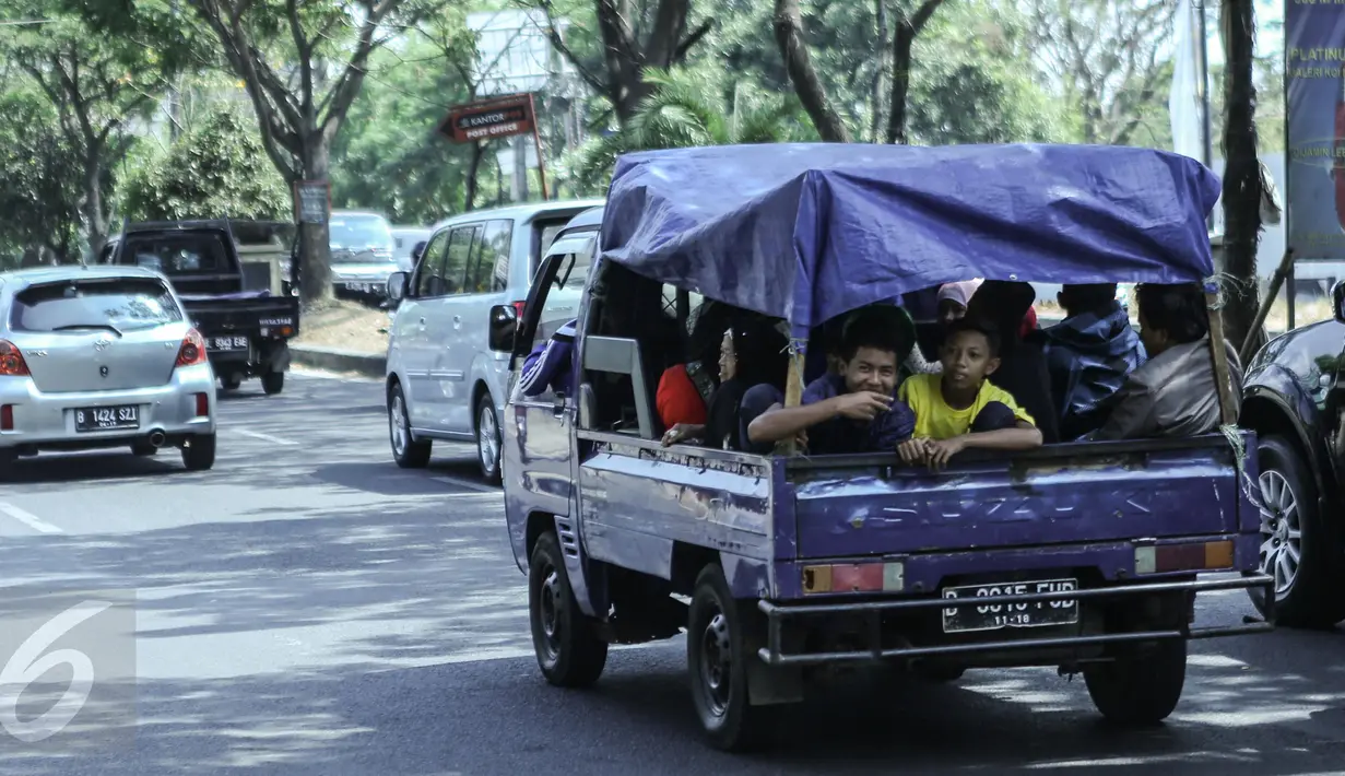 Sejumlah warga menggunakan mobil bak terbuka dengan beratapkan terpal di Jakarta, Minggu (19/7/2015). Meskipun membahayakan, mobil pick up menjadi pilihan warga untuk bersilaturahmi saat momen Lebaran. (Liputan6.com/Faizal Fanani)