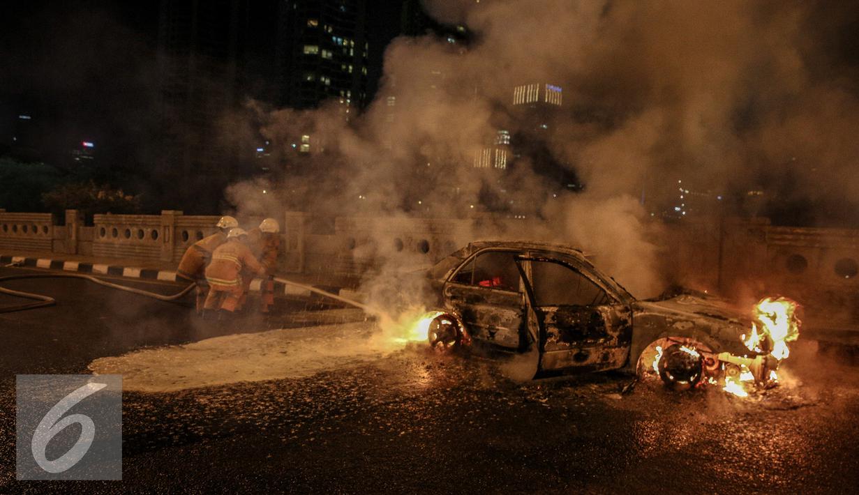 Petugas berusaha memadamkan api mobil yang terbakar di jalan layang Latuharhari, Jakarta, Kamis (18/9/2015). Diduga kebakaran akibat konsleting listrik yang terjadi dibagian depan kap mobil. (Liputan6.com/Faizal Fanani)