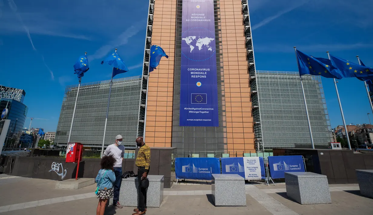 Orang-orang mengenakan masker terlihat di depan gedung kantor pusat Komisi Eropa di Brussel (18/5/2020). Belgia pada Senin (18/5) memasuki pelonggaran pembatasan tahap kedua dengan sekolah-sekolah membuka kembali beberapa kelas di bawah persyaratan organisasi yang ketat. (Xinhua/Zhang Cheng)