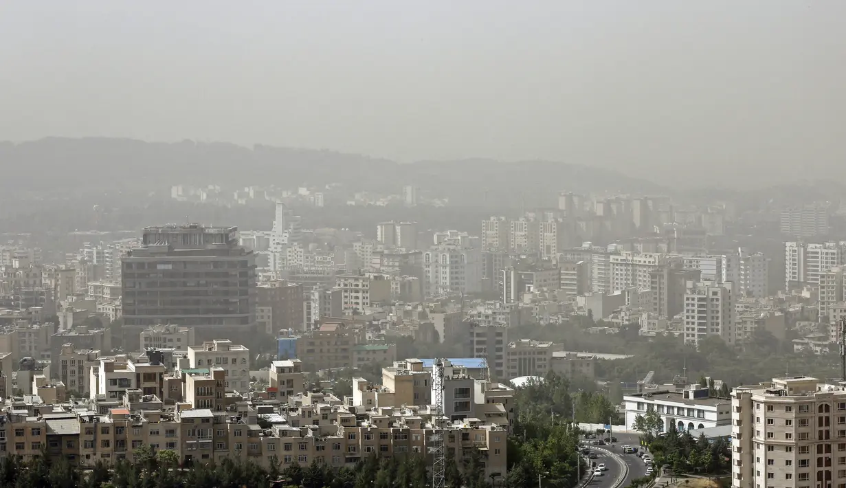 Badai pasir melanda gedung-gedung di utara ibu kota Iran, Teheran pada 17 Mei 2022. Kantor-kantor pemerintah, serta sekolah dan universitas diumumkan ditutup di banyak provinsi di Iran karena kondisi "cuaca tidak sehat" dan badai pasir yang menyelimuti, menurut laporan media pemerintah. (AFP)