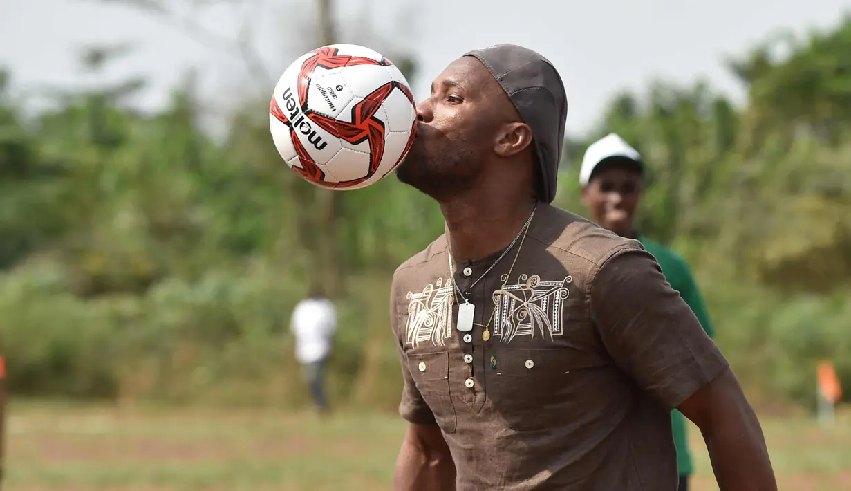 Mantan penyerang Chelsea, Didier Drogba berusaha mengontrol bola saat bermain dengan murid-murid saat peresmian sekolah di Pokou-Kouamekro, dekat Gagnoa, Pantai Gading tengah barat (17/1). (AFP Photo/Sia Kambou)