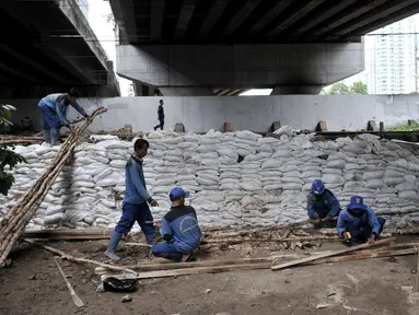 Pekerja Sudin Sumber Daya Air Jakpus menyelesaikan penutupan lubang rembesan di Tanggul Kanal Banjir Barat, Latuharhari, Minggu (5/1/2020). Penutupan untuk mengantisipasi tanggul jebol setelah diketahui terdapat rembesan di sejumlah titik akibat debit air KBB meningkat. (merdeka.com/Iqbal Nugroho)