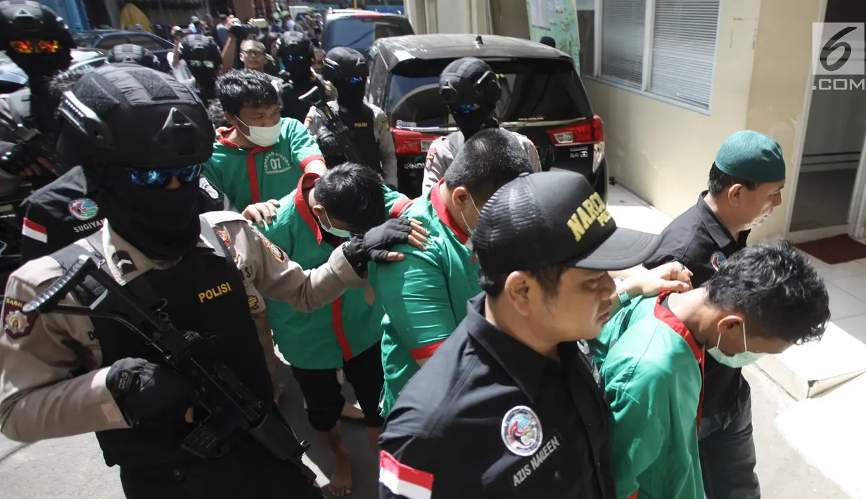 Petugas mengawal tersangka saat menggelar rilis pengungkapan 1,3 ton ganja di Polres Jakarta Barat, Kamis (4/1). Dalam penyelundupan tersebut, petugas berhasil menyita 1,3 ton ganja  dengan enam orang tersangka. (Liputan6.com/Arya Manggala)