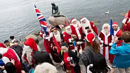 Sinterklas dari penjuru dunia berfoto di patung Little Mermaid, Denmark, Senin (24/7). Kongres ini diadakan di taman hiburan Bakken dekat Kopenhagen sejak 1957 dan selalu pada musim panas saat Sinterklas libur. (Tobias Nicolai/Ritzau Foto via AP)